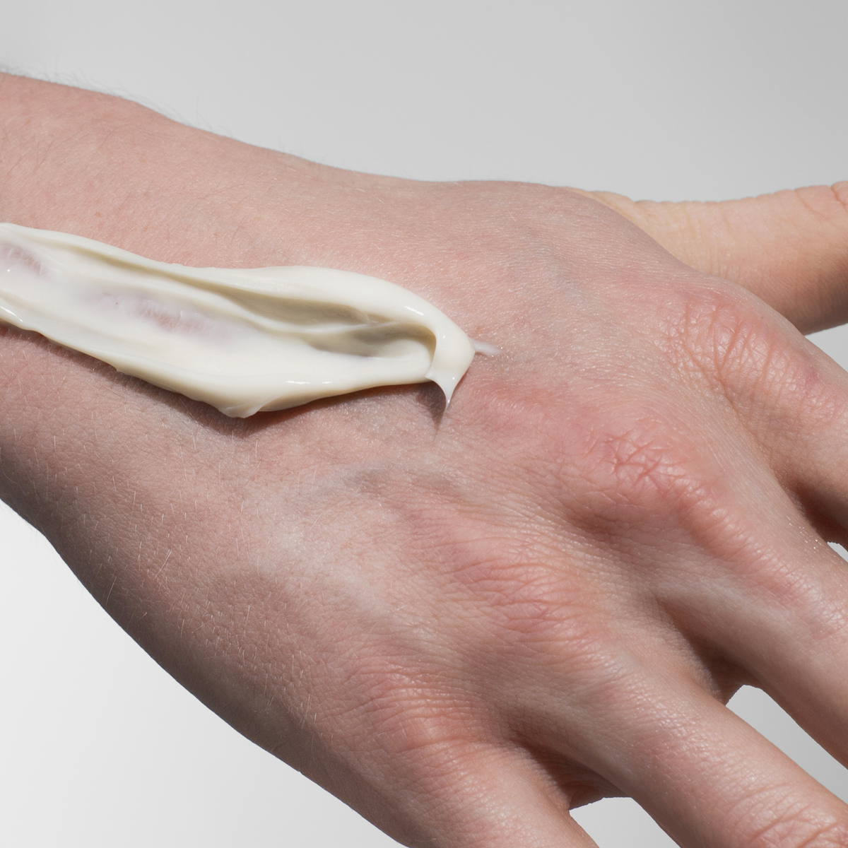 Nahaufnahme einer Hand mit einem Streifen Scandinavian Biolabs Firm Hybrid Clay auf dem Handrücken.
