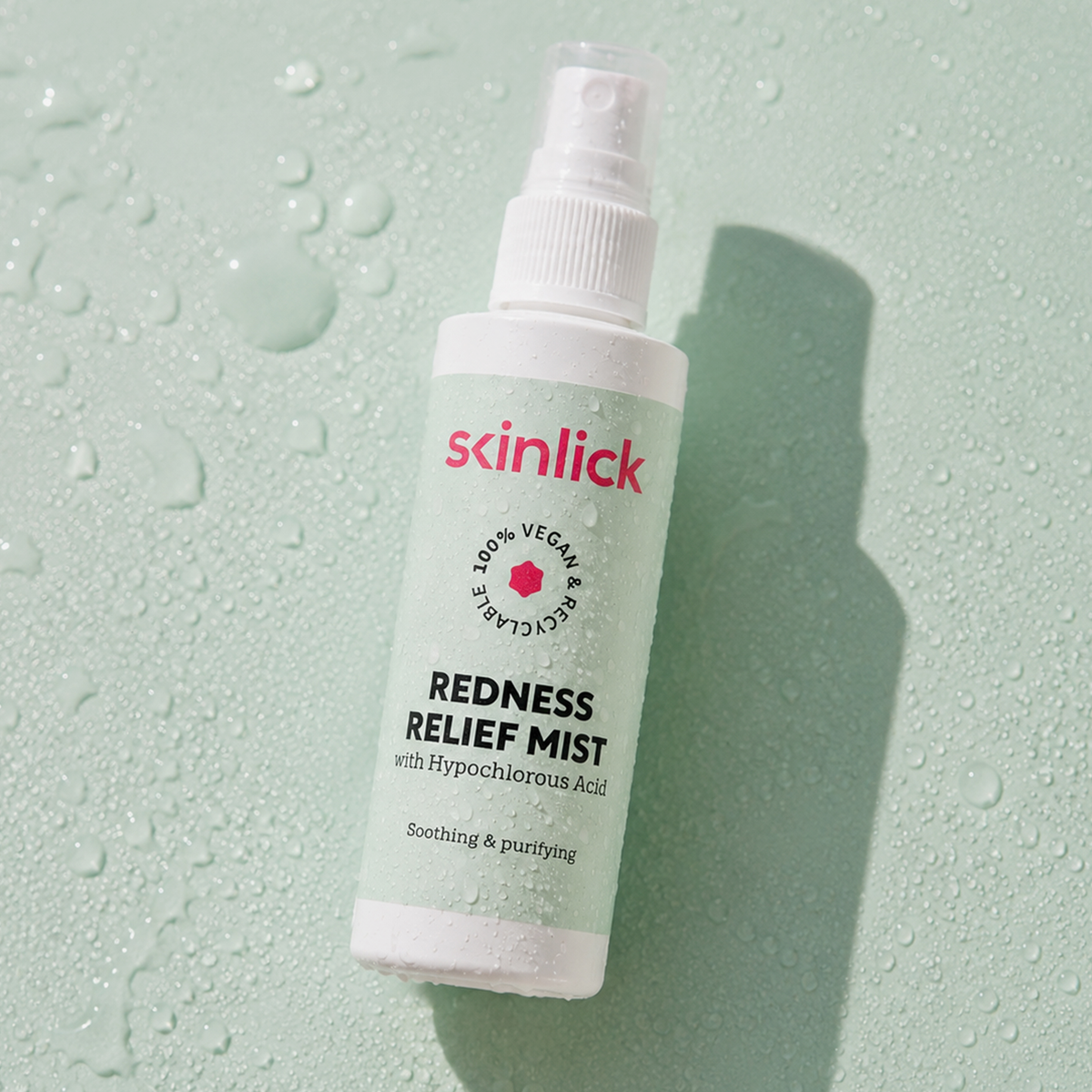Eine Skinlick Redness Relief Mist-Sprühflasche auf einer nassen Oberfläche.