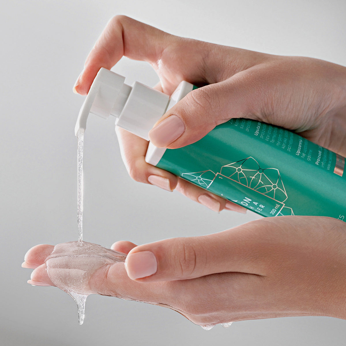 Eine Person gibt Clarion 2 % BHA Cleanser, ein klares Gel aus einer grünen Pumpflasche, vor einem neutralen Hintergrund auf die Hand.