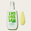 Weiße Flasche des Fox Tan Rapid Mist Fragrance Free neben einem gelbem Produkt-Swatch auf hellem Untergrund.