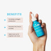 Eine Hand hält eine blaue Flasche Hyaluronsäure-Vitamin-C-Serum, das die Kollagenproduktion ankurbelt, Falten glättet und den Hautton ausgleicht.