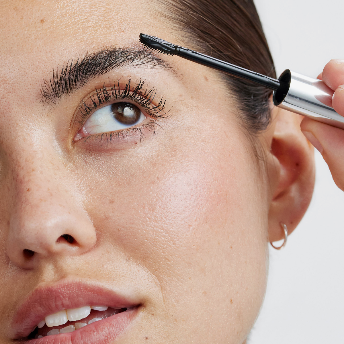 Eine Person, die das XLASH Brow Booster-Augenbrauengel mit einem Applikator aufträgt.