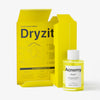 Die leuchtend gelbe Dryzit®-Verpackung hat eine offene Klappe mit einem Diagramm und einer Zutatenliste. Vorne befindet sich eine 30-ml-Flasche Acnemy Dryzit Spot Drying Lotion, die Zinkoxid für reine Haut und Salicylsäure zur effektiven Bekämpfung von Hautunreinheiten enthält.