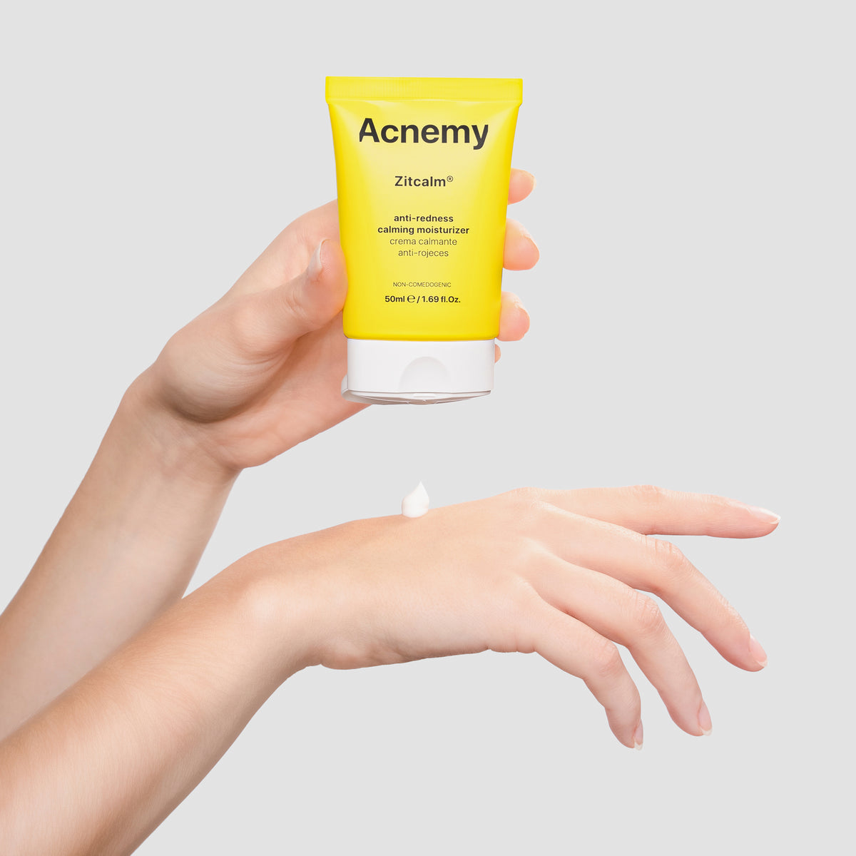 Hände, die den Acnemy Zitcalm Moisturizer aus einer gelben Tube auf die Haut auftragen.