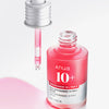 Eine Pipette schwebt über einer offenen rosa Flasche Niacinamide 10 % + TXA 4 % Serum, daneben befindet sich verschüttete Flüssigkeit.