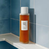 In einem blau-gefliesten Badezimmerregal steht das Ginseng Essence Water von Beauty of Joseon