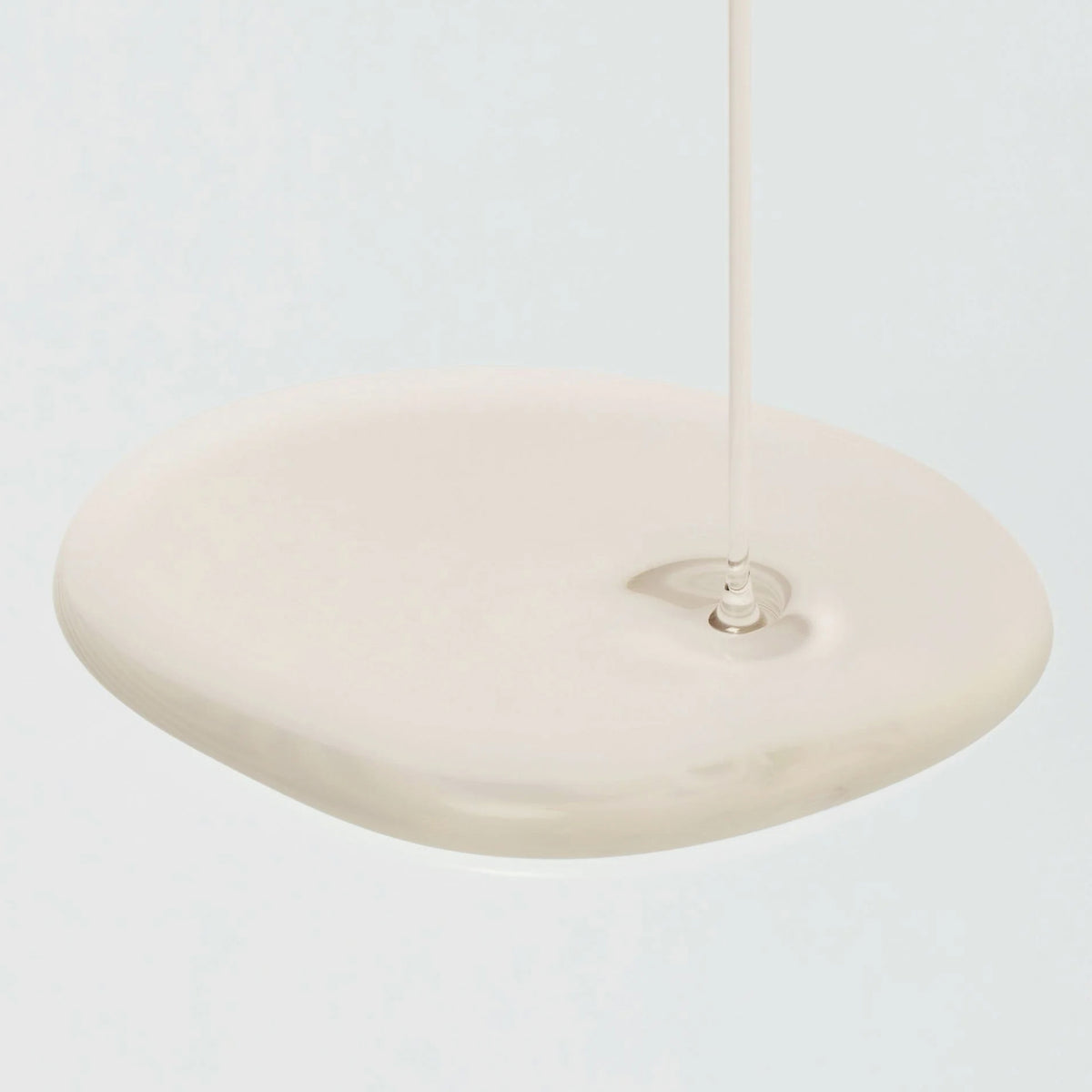 Eine Tropfen Glow Repleneshing Rice Milk auf einer hellen Oberfläche.