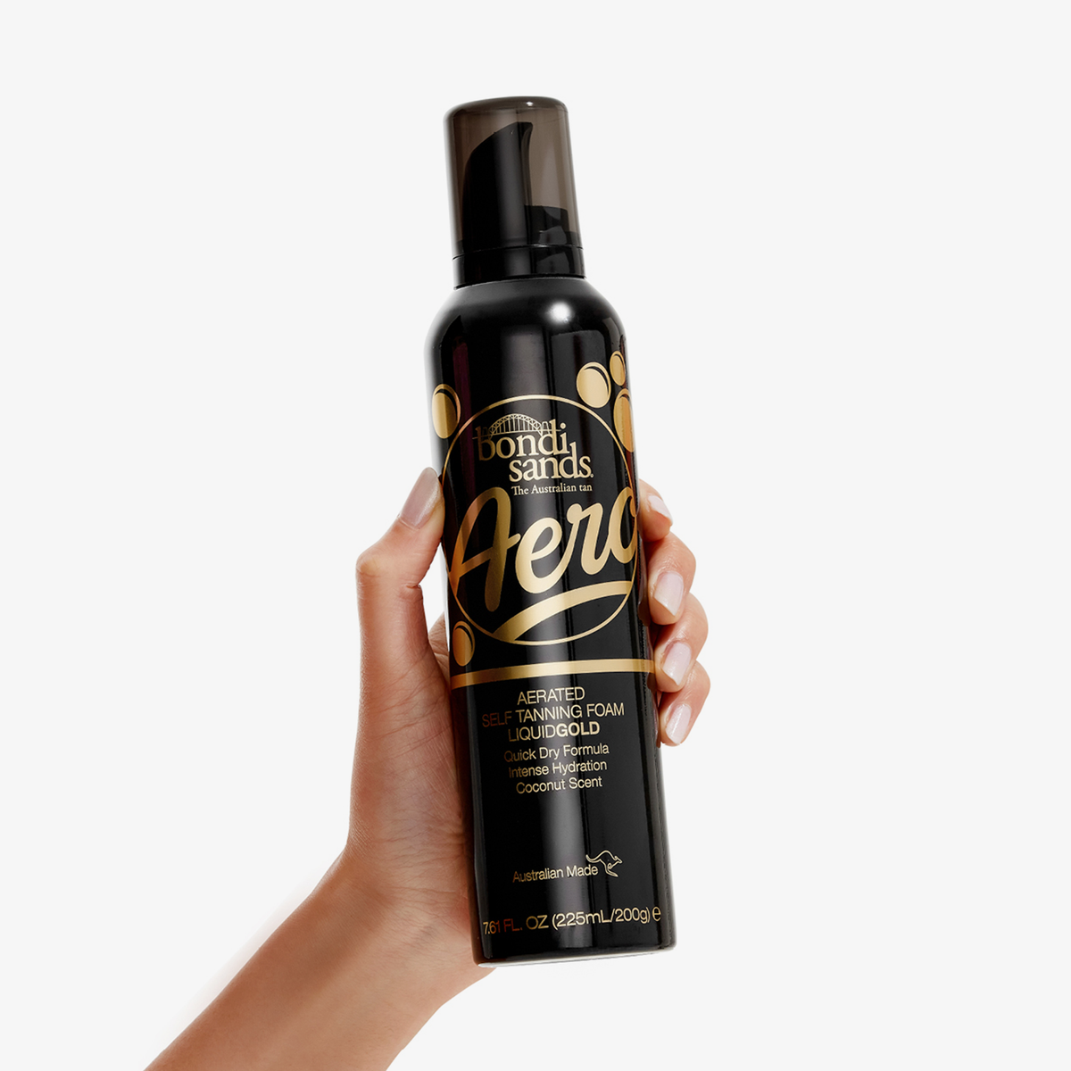 Eine Hand hält eine Flasche Bondi Sands Aero Self Tanning Foam Liquid Gold vor einem weißen Hintergrund.