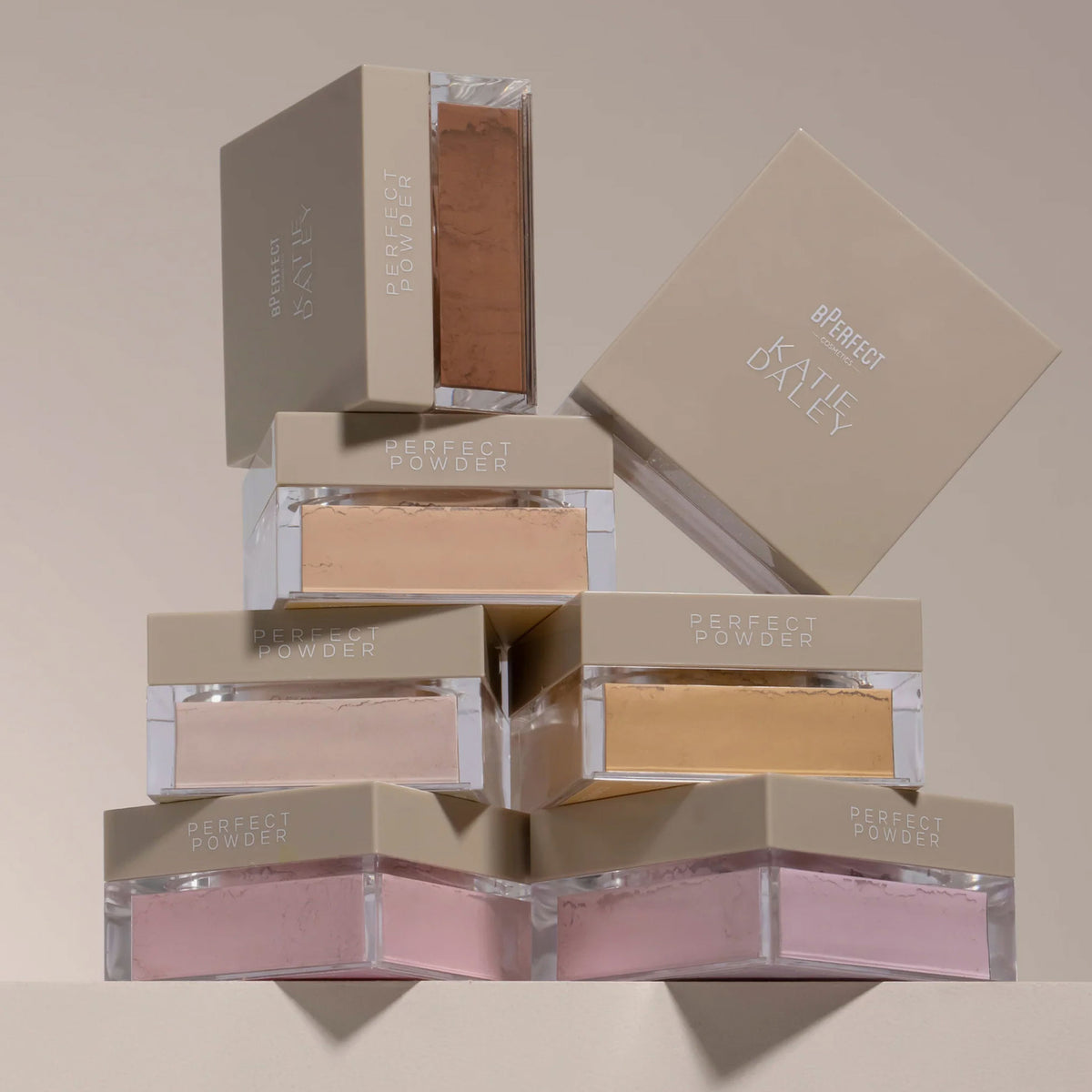 Die BPerfect Cosmetics x Katie Daley Perfect Powders gestapelt vor einem beigen Hintergrund.