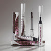 Mehrere BPerfect Lash Out Mascaras Brown mit Verpackungen, präsentiert vor grauem Hintergrund.