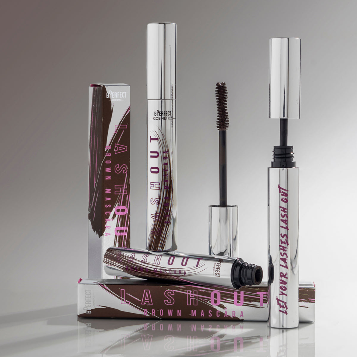 Mehrere BPerfect Lash Out Mascaras Brown mit Verpackungen, präsentiert vor grauem Hintergrund.