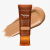 Eine Tube Yummy Skin Serum Tint 6 vor einem warmbeigem Farbmuster.