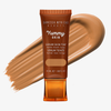 Eine Tube Yummy Skin Serum Tint 9 vor einem warmem hellbraunem Farbmuster.