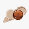 Runde geöffnete bronzefarbene Dose des Yummy Skin Blurring Balm Powder vor einem Farbstreifen der Shade 1.