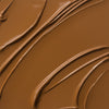 Nahaufnahme der cremigen Textur des Yummy Skin Lift & Flex Concealer 13 in warmem Braun.