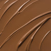 Nahaufnahme der cremigen Textur des Yummy Skin Lift & Flex Concealer 14 in Mittel- bis Dunkelbraun.