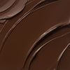 Nahaufnahme der cremigen Textur des Yummy Skin Lift & Flex Concealer 19 in dunklem Schokobraun.