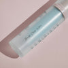 Mattierte Flasche „Cooling Blur Mattifying Primer“ mit dem Text „Beauty Starts Within …“, auf einer blassrosa Oberfläche liegend.
