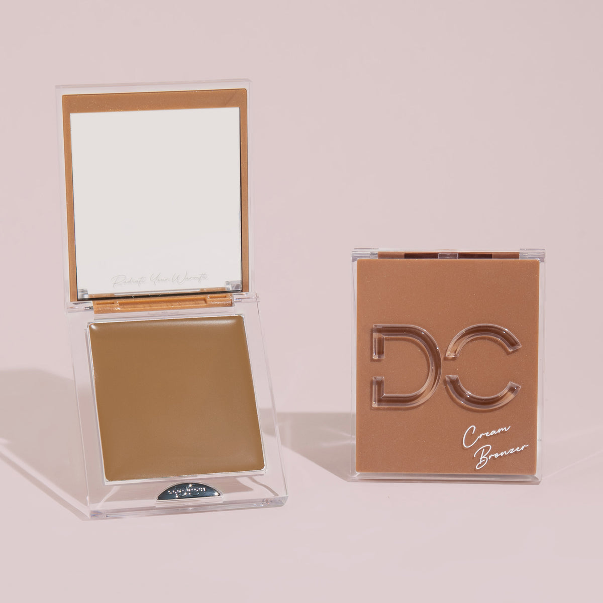 Zwei quadratische Silktone Cream Bronzer-Kompaktdosen – eine geöffnet mit Produkt und Spiegel, eine geschlossen mit dem Silktone Cream Bronzer-Etikett.