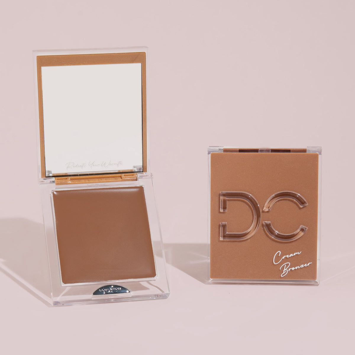 Zwei Silktone Cream Bronzer-Kompaktdosen, eine geöffnet mit Spiegel und Produkt, die andere geschlossen und auf einem hellbeigen Hintergrund präsentiert.