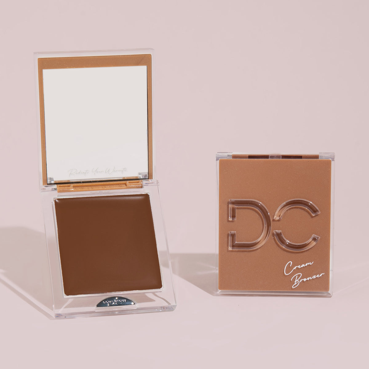 Silktone Cream Bronzer-Kompaktpackungen – eine geöffnet, um den Bronzer und den Spiegel freizugeben, eine geschlossene – präsentiert auf einem neutralen Hintergrund.