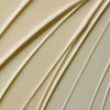Nahaufnahme der cremigen beigen Textur des Glow-C Daily Moisturiser mit strukturierten, gewellten diagonalen Linien.