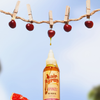 Eine Rapunzel-Haarsirupflasche, aus der Öl tropft, Kirschen, die an einer Wäscheleine hängen, und eine Grapefruitscheibe in der Nähe.