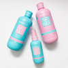 Das Hairburst Volume & Growth Elixir Bundle mit drei Produkten in blauen und rosa Flaschen ist auf einer weißen Oberfläche.