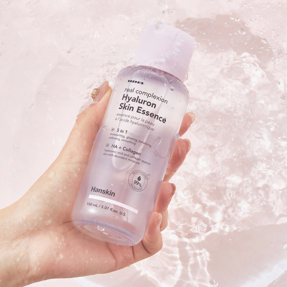 Eine Hand hält eine Flasche Real Complexion Hyaluron Skin Essence über spritzendes Wasser.