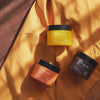 Drei Tiegel mit Pore Cleansing Balm von Hanskin auf gelbem Stoff präsentiert im Sonnenlicht.