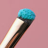 Nahaufnahme eines Pinsels mit Opal Moonstone Loose Multichrome Eyeshadow Clever Clogs in leuchtendem Türkis.