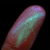 Nahaufnahme einer Fingerspitze, die in den Opal Multichrome Loose Eyeshadow Birdsong getaucht wurde und pink-grün glitzert.