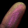 Nahaufnahme einer Fingerspitze, die in den Opal Multichrome Loose Eyeshadow Cozy getaucht wurde und gelb-grün und pink-lila glitzert.