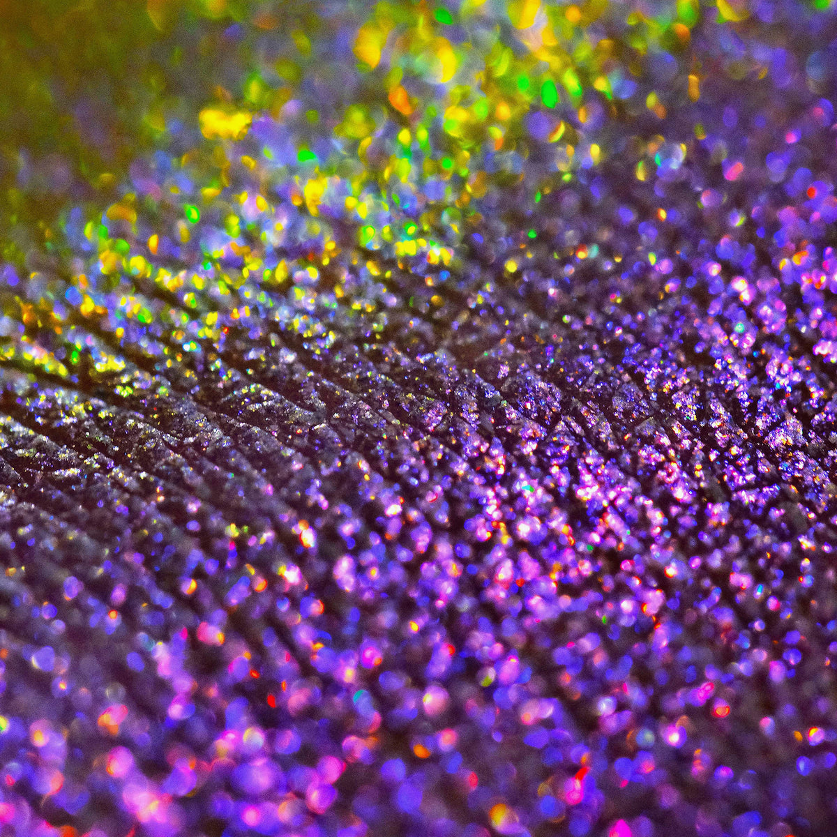 Nahaufnahme der Textur des des Opal Multichrome Loose Eyeshadow Night Kiss; ein gelblich-grün und lila schimmerndes Pigment.