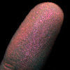 Nahaufnahme einer Fingerspitze, die in den Opal Multichrome Loose Eyeshadow Skylight getaucht wurde und pink-orange glitzert.
