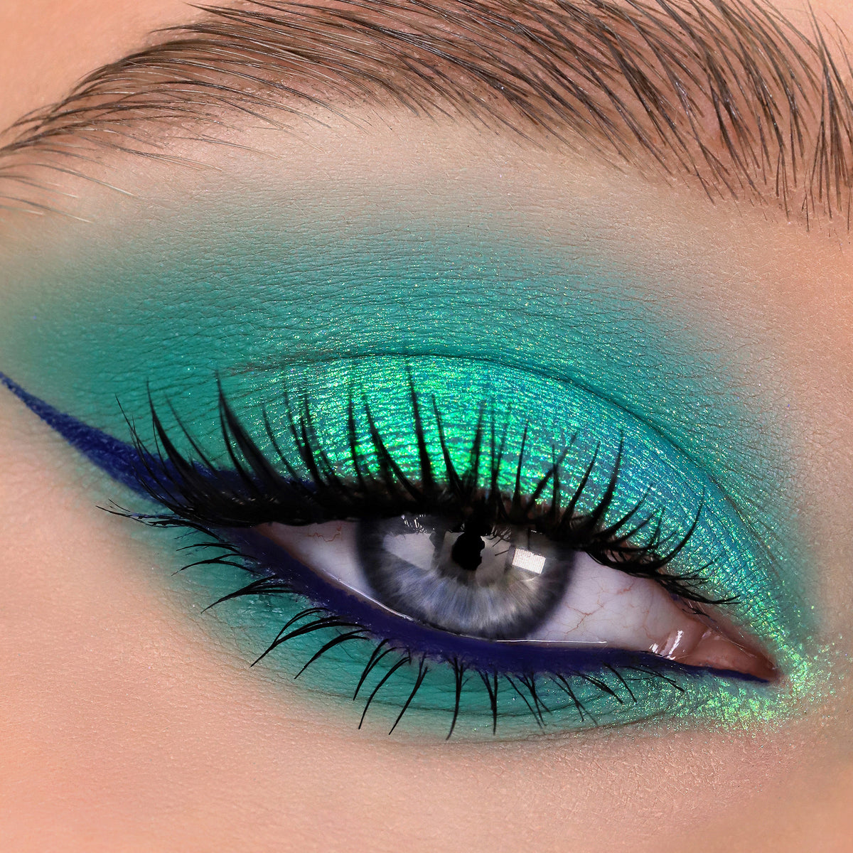 Nahaufnahme eines Auges mit dramatischem Eyeliner und grünlich-türkis schimmerndem Opal Multichrome Loose Eyeshadow in Sweetdreams.