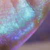 Nahaufnahme des seidigen Gel-Lidschattens Opal Shadow Potion auf der Haut, der schillernde, schimmernde blaue, violette und grüne Highlights zeigt.