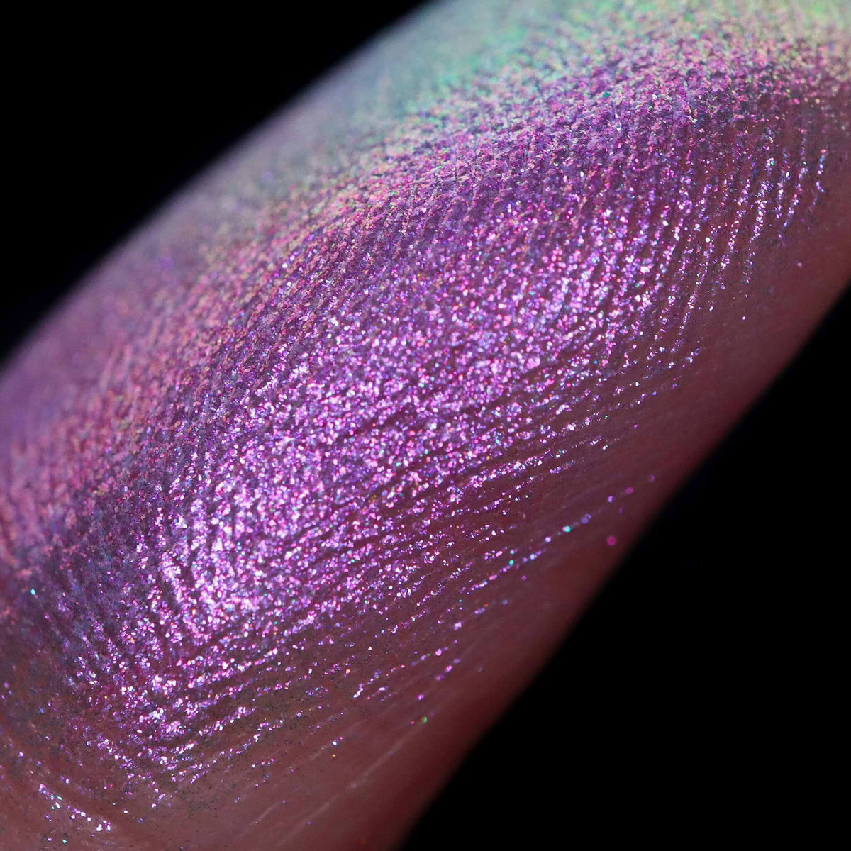 Nahaufnahme einer Fingerspitze, die in den Pastel Duochromes Loose Eyeshadow Dolly getaucht wurde und lila und rosa glitzert.