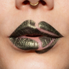 Nahaufnahme geschminkter Lippen mit grün-metallisch glänzendem Lippenstift (Crayon Gemma) und bewusst ausgesparten Stellen, die ein verspieltes, grafisches Muster ergeben.