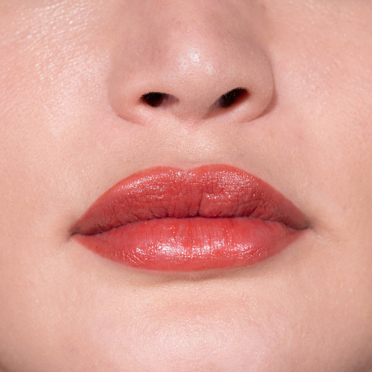 Nahaufnahme von glänzenden, rostorangen Lippen mit dem Fantastick Lipstick Poppy von LH Cosmetics.