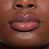 Nahaufnahme von Lippen einer Person mit dunklem Teint mit transparentem glitzerndem Glazed Drip Lipgloss von LH Cosmetics.