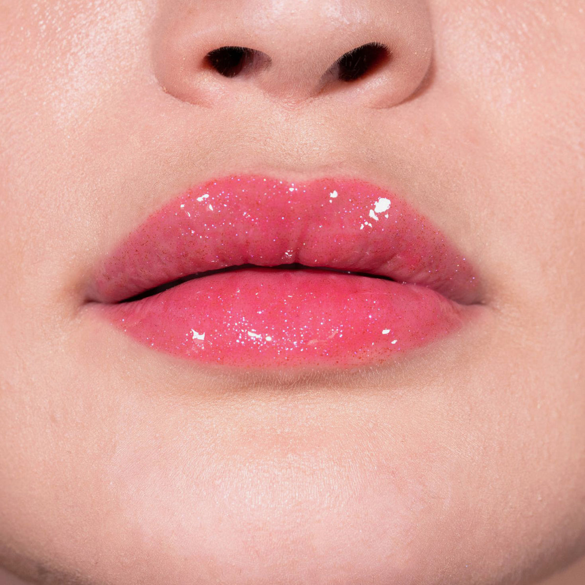 Nahaufnahme von Lippen einer Person mit hellem Teint mit pink glitzerndem Glazed Sugar Lipgloss von LH Cosmetics.