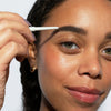 Eine Frau mit mittlerem Hautton und grünen Augen trägt den Infinity Brow Pen Dark Brown auf ihre Augenbrauen.