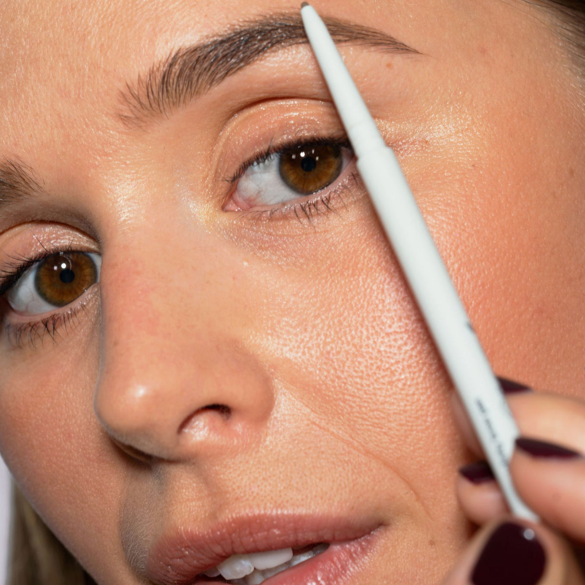 Eine Frau mit hellem Hautton und braunen Augen trägt den Infinity Brow Pen Medium Brown auf ihre Augenbrauen.