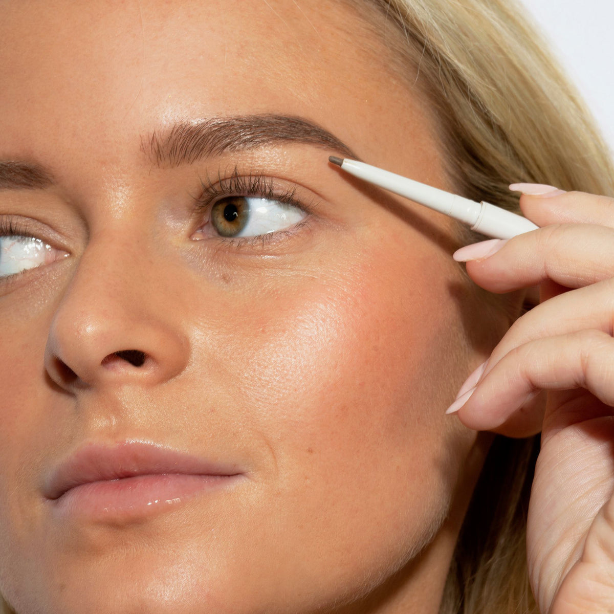 Eine Frau mit mittlerem Hautton und blondem Haar trägt den Infinity Brow Pen Taupe auf ihre Augenbrauen.