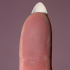 Eine Nahaufnahme einer Fingerspitze mit detaillierten Rillen, die The Single von LH Cosmetics vor einem unifarbenen Hintergrund zeigt.