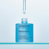 Offene blaue Flasche Living Proof Scalp Care Density Serum mit einer Pipette, die darüber einen Tropfen freigibt.