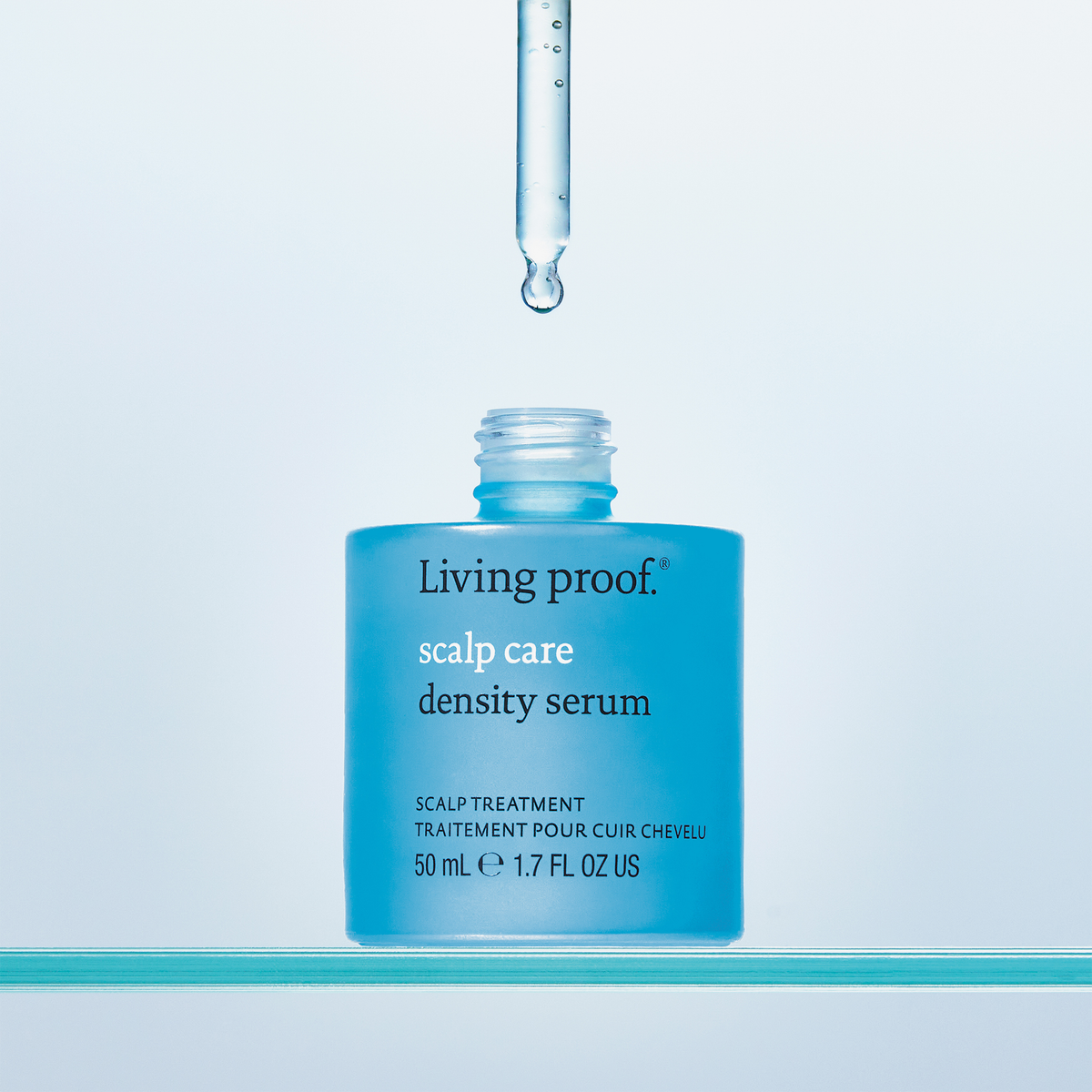 Offene blaue Flasche Living Proof Scalp Care Density Serum mit einer Pipette, die darüber einen Tropfen freigibt.