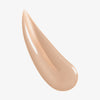 Nahaufnahme der cremigen beigen Textur des Lumene INVISIBLE ILLUMINATION Glow Beauty Serum Universal Light.
