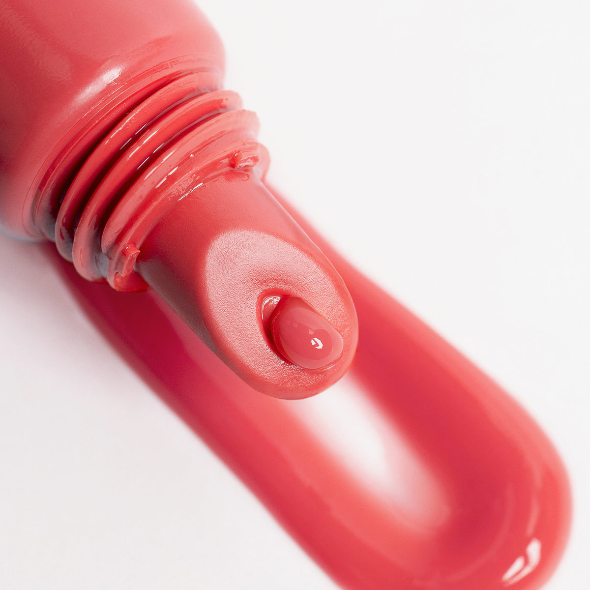 Nahaufnahme des Lip Glow Oil Balm Juicy vor Swatch des Produktes; korallenrosa Textur tritt aus dem Applikator
